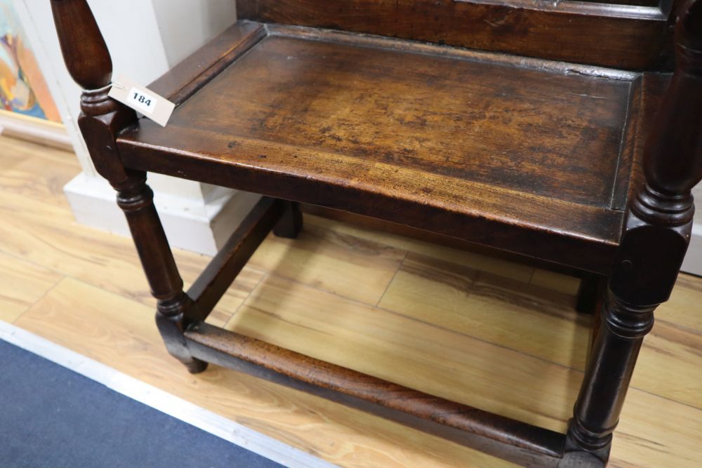 An 18th century oak panel back open armchair with wood seat,